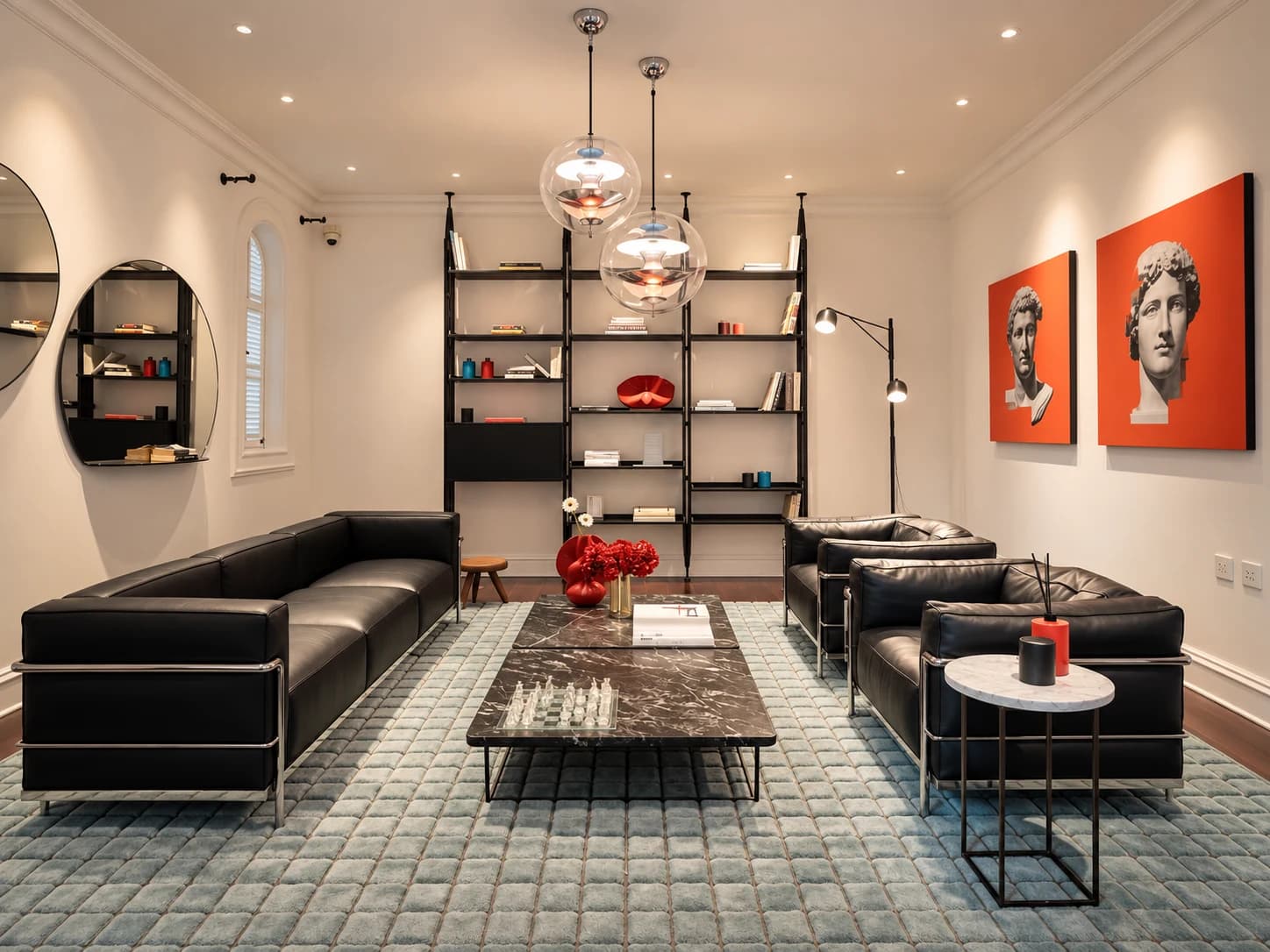 Không gian phòng khách với sofa da đen, đèn treo và kệ trưng bày