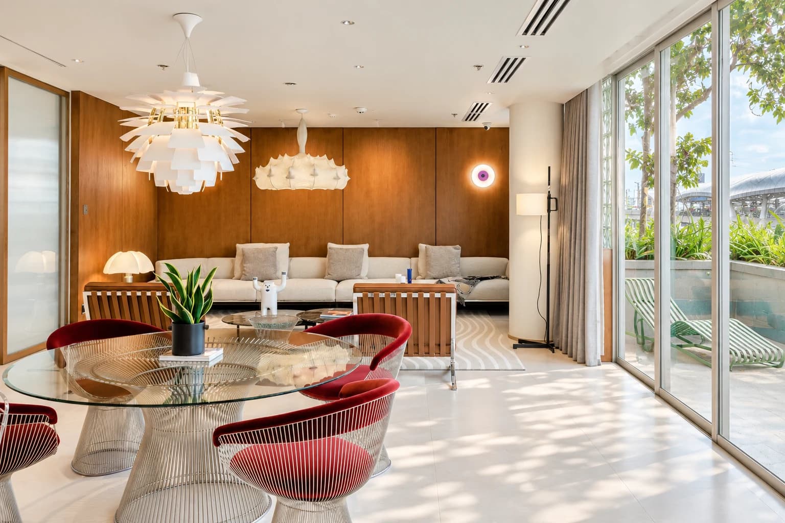 A living room with a dining table, decorative lighting and full-height windows