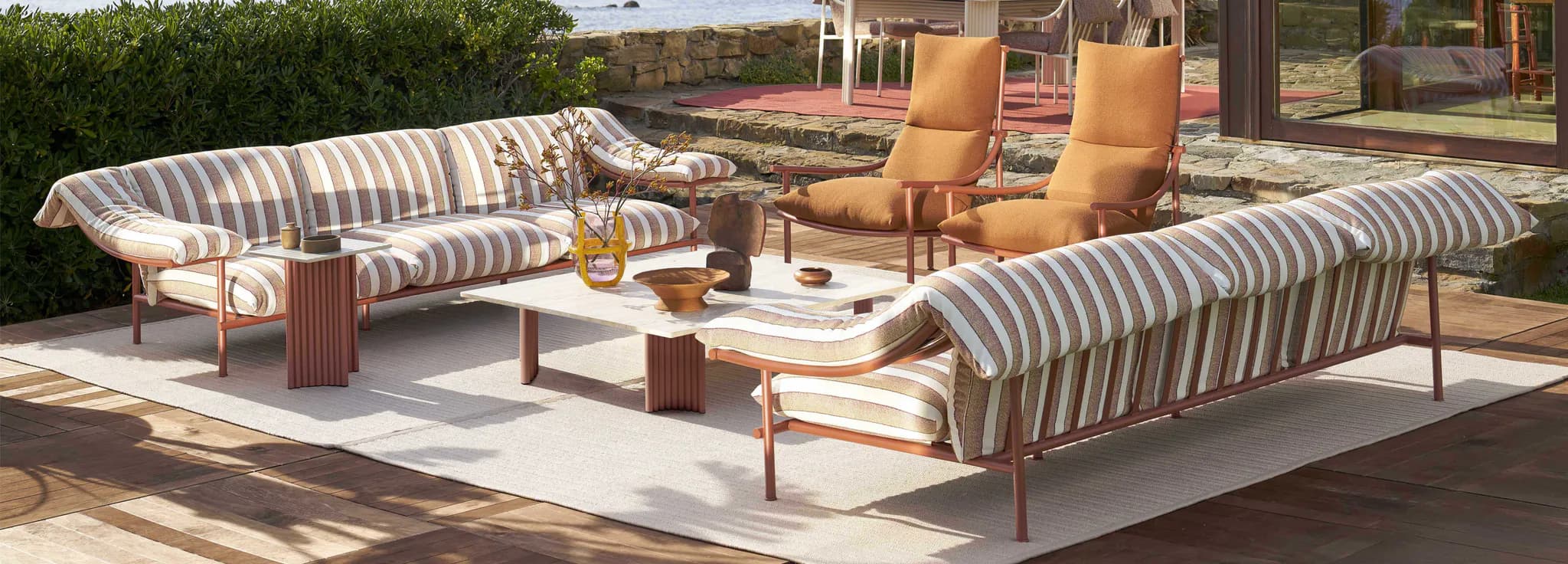Không gian lounge ngoài trời với sofa sọc và ghế cam